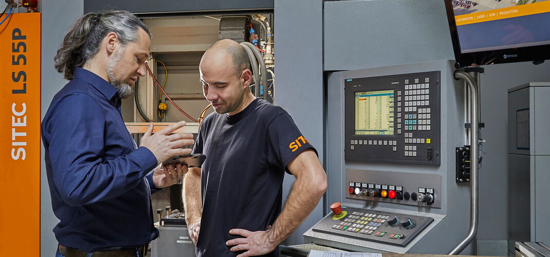 Two service engineers in conversation at a machine