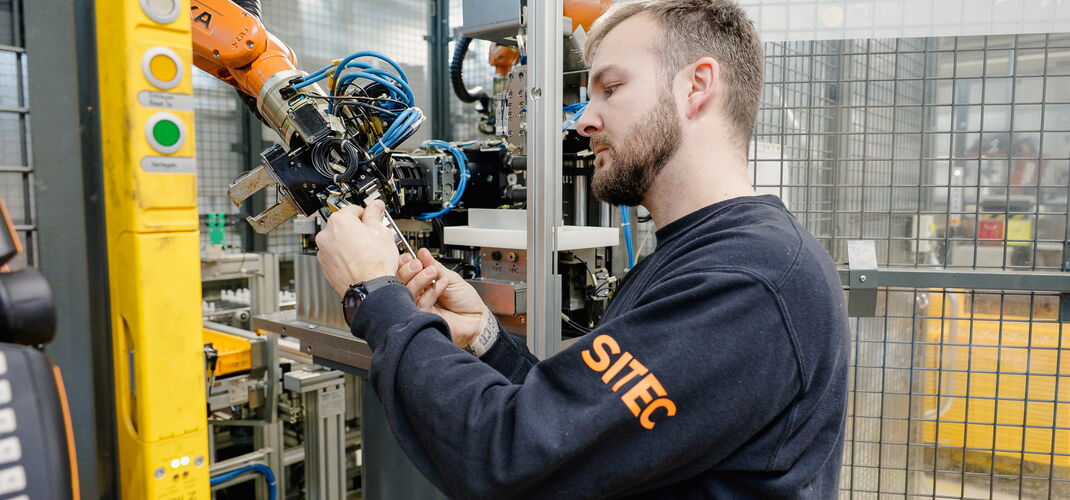 A service technician carries out maintenance on a robot arm