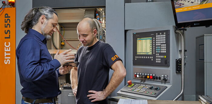 Two service engineers in conversation at a machine